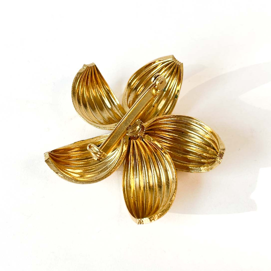 Broche flor dorada con perla central.