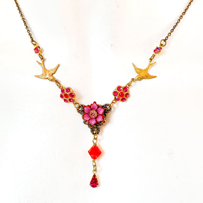 Collar Golondrinas Mensajeras dorado con flores y cristales rosa y fucsia 