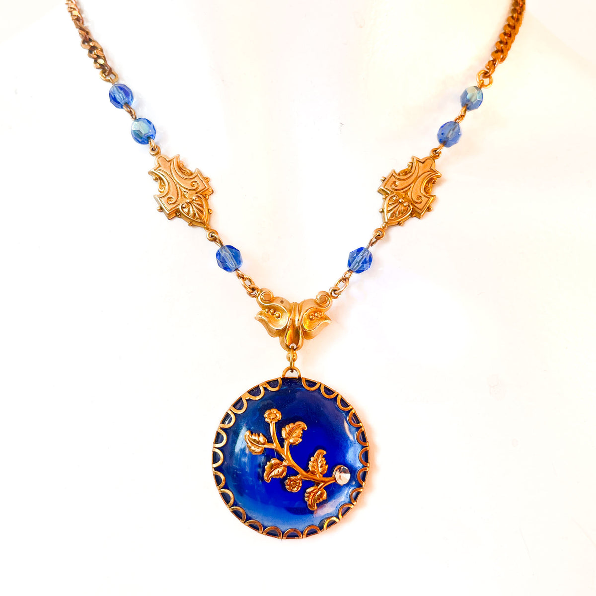 Collar artesanal con medallón azul cobalto, motivos florales dorados y cristales azules de Atelier de Bijoux