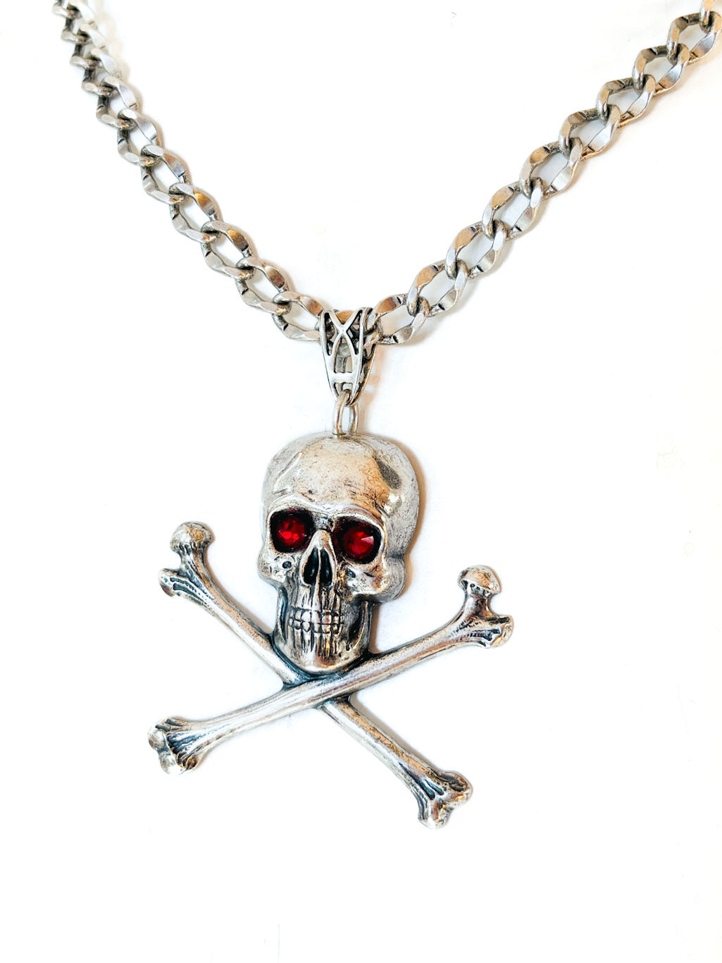 Collar calavera con tibias cruzadas, cristales rojos y cadena en tono plateado