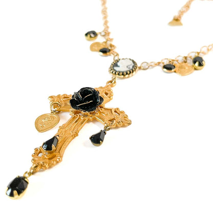 Collar dorado con cruz ornamental, camafeo central, rosa negra y cristales facetados negros.