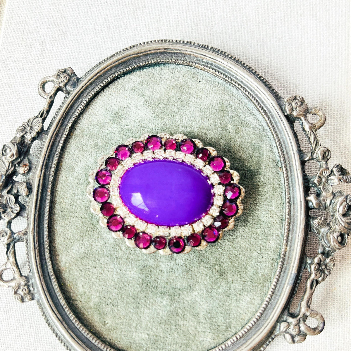broche ovalado con piedra opaca violeta y cristales brillantes 