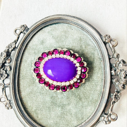broche ovalado con piedra opaca violeta y cristales brillantes 
